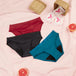 Pack Confort ultime: ensemble de culottes menstruelles Bikini Basic Moderate et serviettes V-Protection, disposées sur une couverture rose, offrant confort pendant les règles.